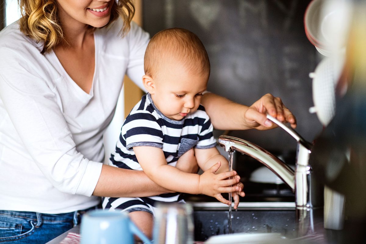 A mom washing her son's hand with water
